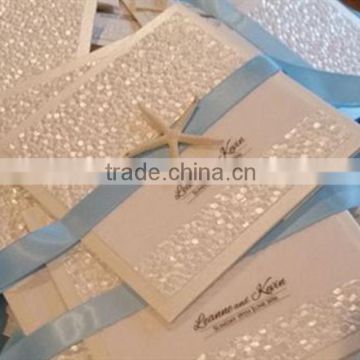 Hot sale white embossed wedding invitation card with blue ribbons & starfish decorations                        
                                                Quality Choice