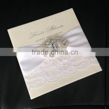 Attractive white lace wedding invitation cards with ivory ribbons and rhinestone brooches